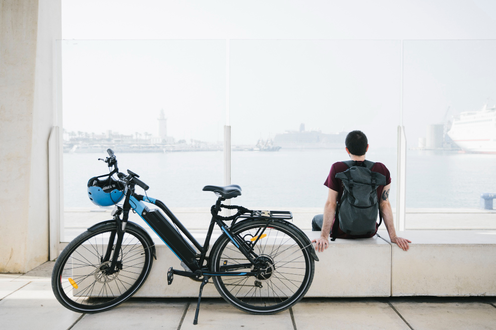 un homme assis à côté de son vélo électrique