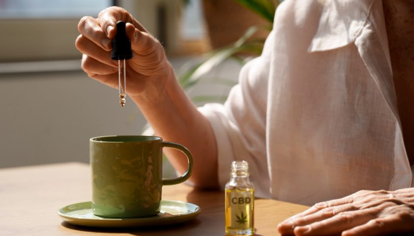 une femme qui met des gouttes de cbd dans une tasse